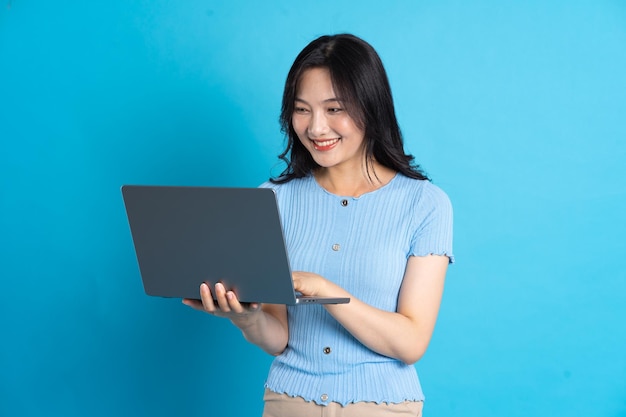 Portrait of asian girl using laptop on blue background