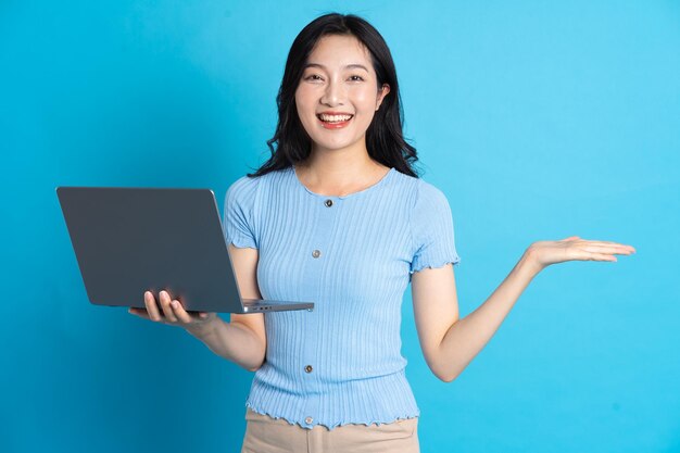 Portrait of asian girl using laptop on blue background