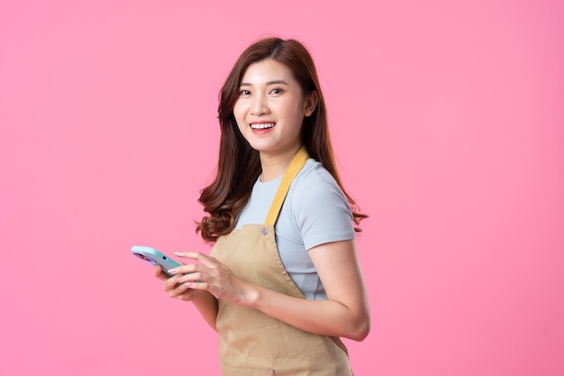 Portrait of asian girl wearing apron on pink background