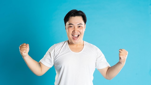 Portrait of an Asian guy posing on a blue background