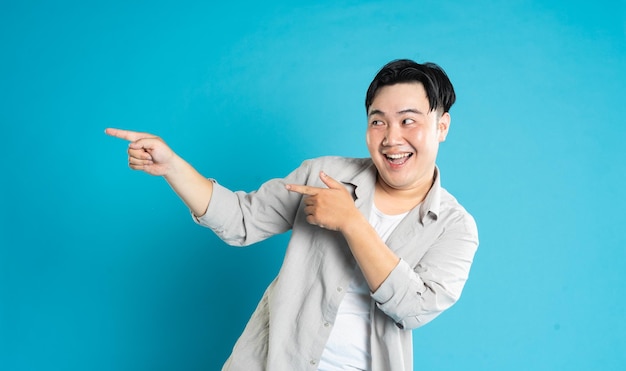 Portrait of an Asian guy posing on a blue background