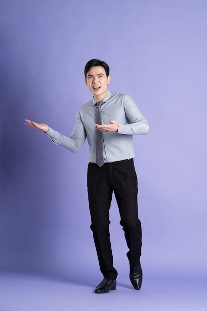 Portrait of Asian male businessman standing and posing on purple background