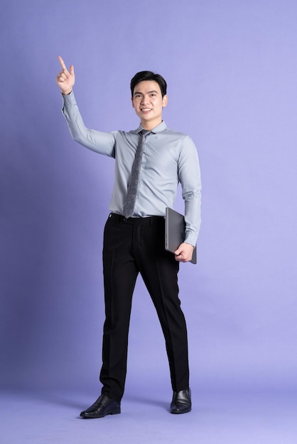 Portrait of Asian male businessman standing and posing on purple background