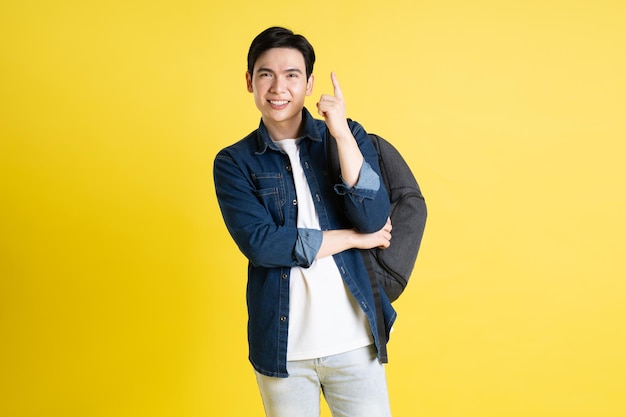 Portrait of Asian male student posing on yellow background