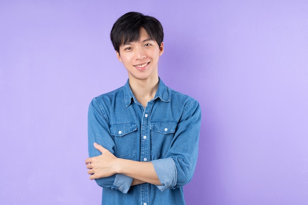 Portrait of Asian man in blue shirt posing on purple background