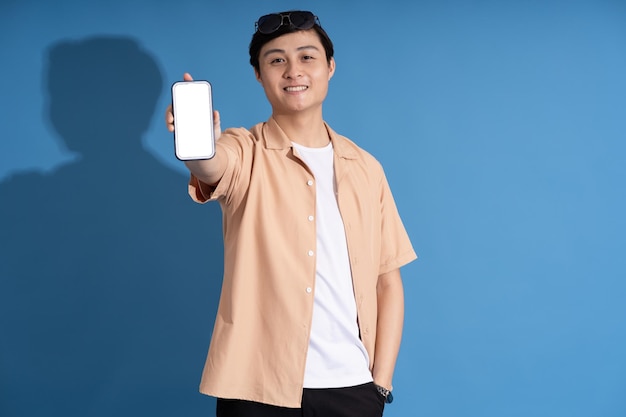 Portrait of Asian man posing on blue background traveling in summer