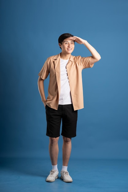 Portrait of Asian man posing on blue background traveling in summer