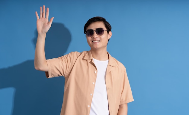 Portrait of Asian man posing on blue background traveling in summer