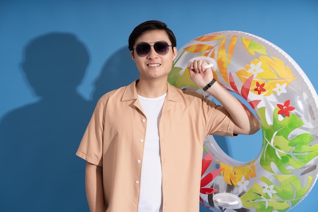 Portrait of Asian man posing on blue background traveling in summer