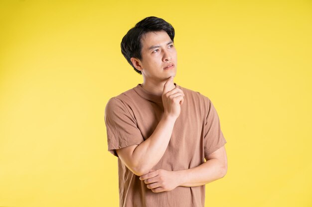 Portrait of asian man posing on yellow background