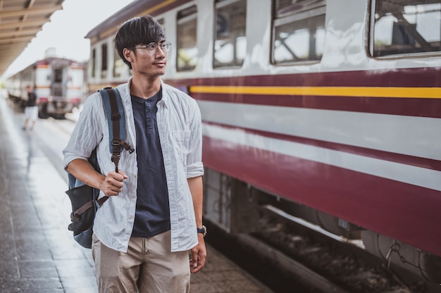 Portrait asian man walking onto a train at a train station for a vacation.Travel concept. Man traveler tourist walking at train station.