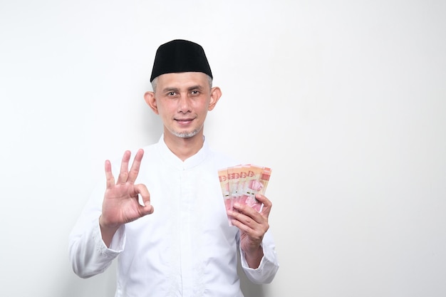 Portrait of Asian Moslem Man holding lots of money in hand, the concept of saving, investing