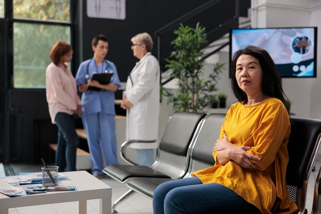 Portrait of asian patient in hospital waiting area having medical appointment with physician doctor. Woman attending checkup consultation with medic to cure illness and get treatment.