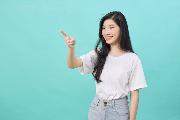 Portrait of Asian teen beautiful young woman smile laughing point finger side away blank copy space