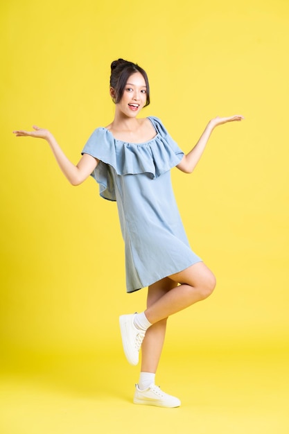 Portrait of Asian woman in skirt posing on yellow background