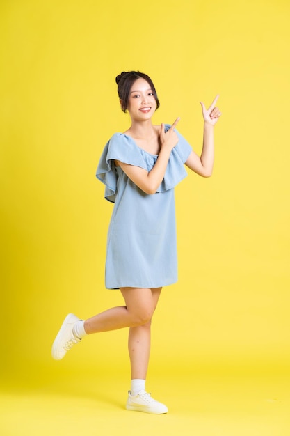 Portrait of Asian woman in skirt posing on yellow background