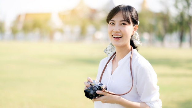 Portrait of asian woman traveler using camera Asia summer tourism vacation concept with the grand palace in a background at Bangkok Thailand