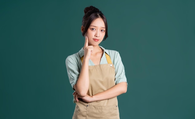 Portrait of Asian woman wearing apron on green background