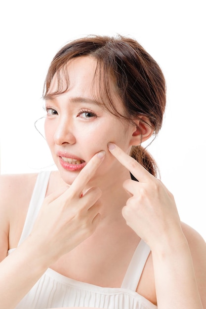 Portrait of Asian woman with a beautiful face and clean fresh smooth skin pimple press Lovely female model with natural makeup in studio Cosmetology Facial treatment Therapy and spa concept