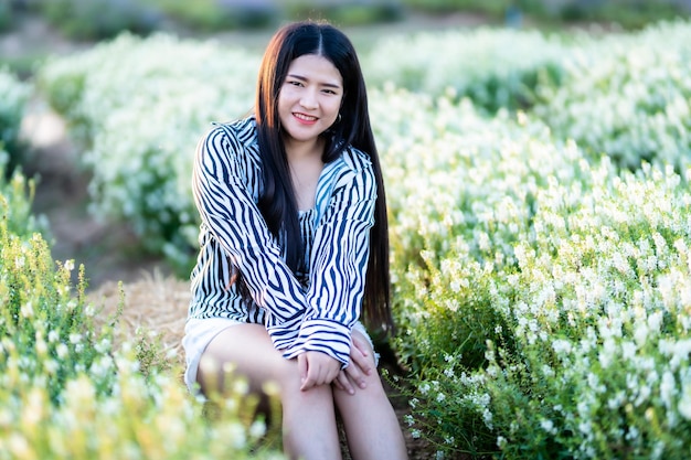 Portrait of asian Young woman happy traveler with black and white pattern dress enjoying in white blooming flower field in the nature garden of in Thailandtravel relax vacation