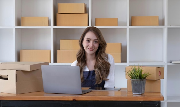 Portrait of Asian young woman SME working with a box at home the workplacestartup small business owner small business entrepreneur SME or freelance business online and delivery concept