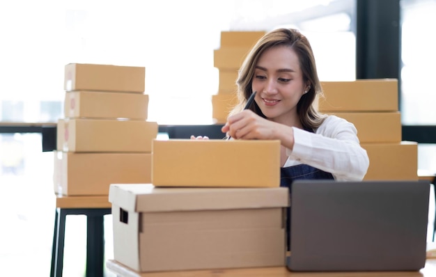 Portrait of Asian young woman SME working with a box at home the workplacestartup small business owner small business entrepreneur SME or freelance business online and delivery concept