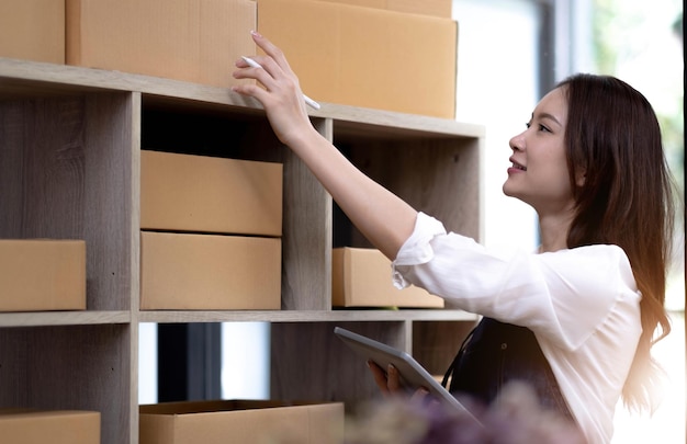 Portrait of Asian young woman SME working with a box at home the workplacestartup small business owner small business entrepreneur SME or freelance business online and delivery concept