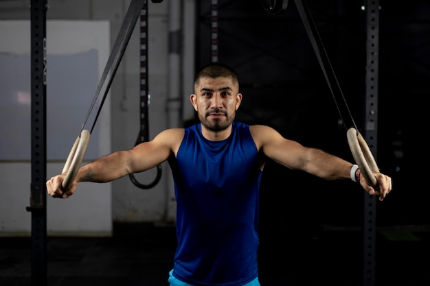 Portrait of an athlete standing leaning on gymnastic rings at a training site