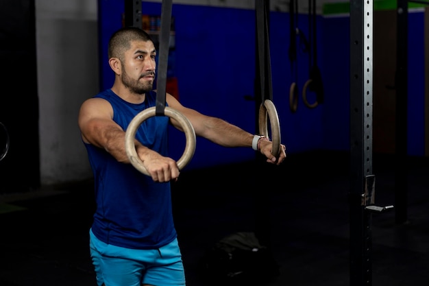 Portrait of an athlete standing leaning on gymnastic rings at a training site