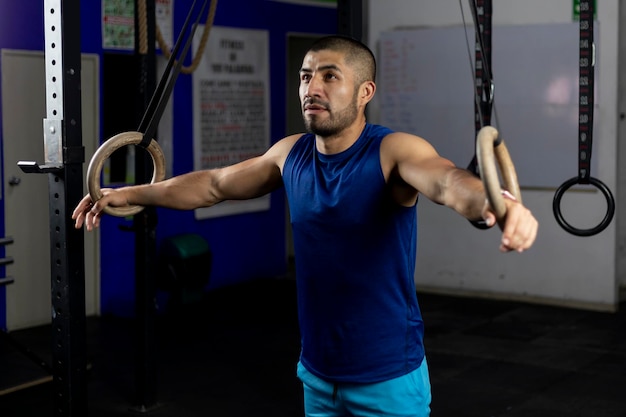 Portrait of an athlete standing leaning on gymnastic rings at a training site