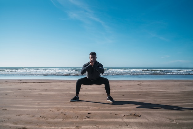 Portrait of an athletic man doing exercise at the beach. Sport and healthy lifestyle concept.