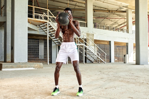 Portrait of athletic workout African American man with ball outdoors in nature sport and healthy concept