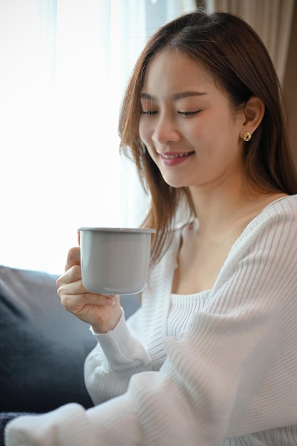 Portrait Attractive Asian female in the living room sipping a morning coffee to start her weekend