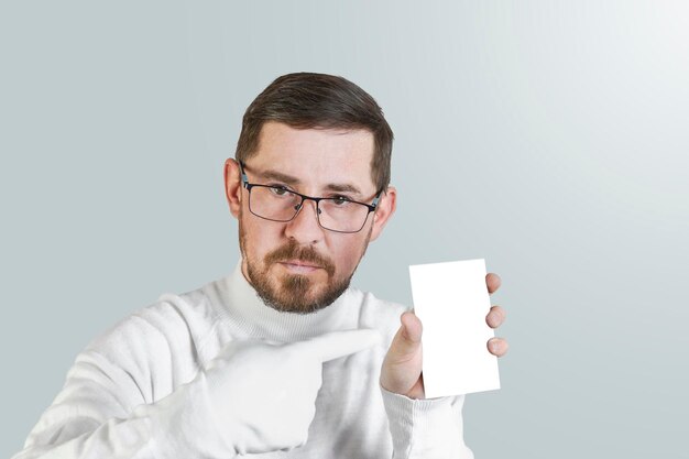 Portrait of an attractive bearded guy in glasses pointing with a finger in a white glove at a business card or ad Isolated pastel colored background Mocap