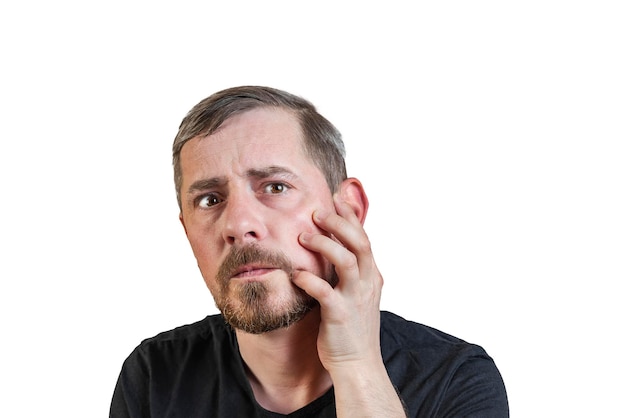 Portrait of an attractive bearded man of European appearance with a slight gray hair on an isolated white background Holds a hand on the cheek Expression of emotions of a man