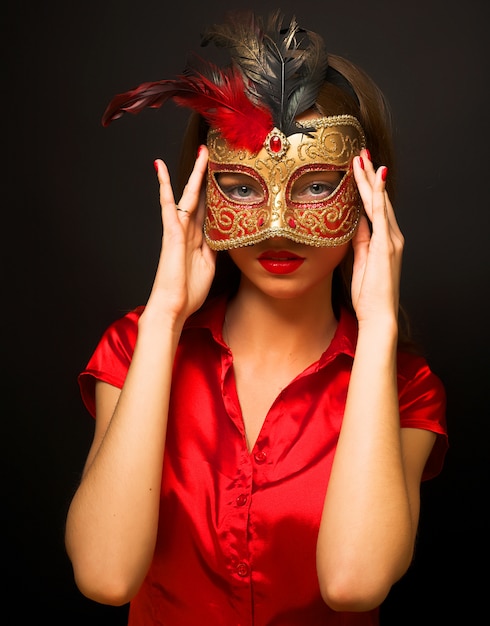 Portrait of attractive beautiful young woman wearing red cold  carnival mask