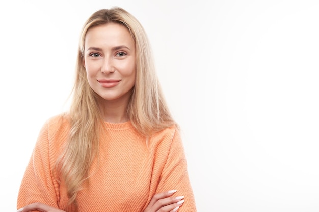 Portrait of attractive blonde girl in orange casual posing and smiling joyfully isolated on white studio background