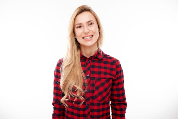 Portrait of attractive blonde girl in plaid red shirt posing and smiling joyfully isolated on white studio background