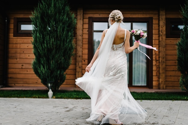 Portrait of an attractive bride with a wedding bouquet dancing and rotating back spinning on a wedding ceremony