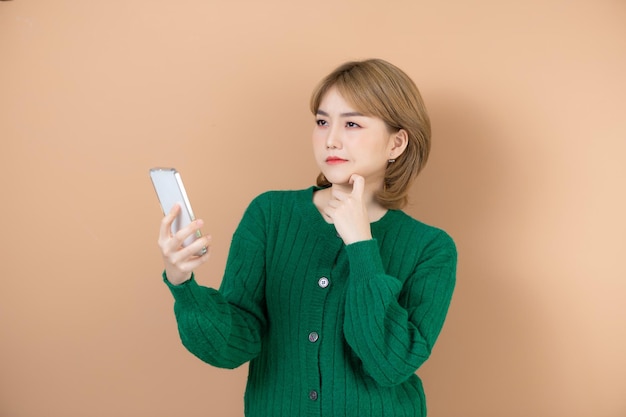 Portrait of attractive cheerful girl using device reading smm post social network isolated on beige background