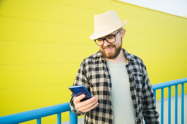 Portrait of attractive cheerful guy using smartphone for scrolling on social media over bright vivid shine vibrant yellow color background