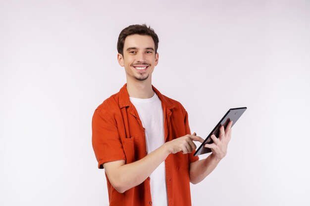 Portrait of attractive cheerful man using device app searching web isolated over white color background Technology and business concept