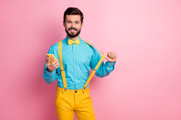 Portrait of attractive confident guy holding cell puling suspender