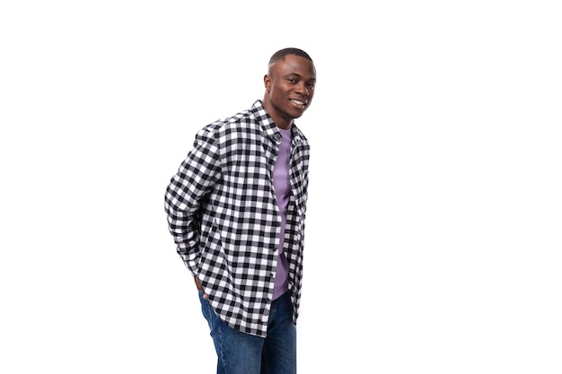 Portrait of attractive dark skinned man in plaid shirt and jeans posing over isolated white