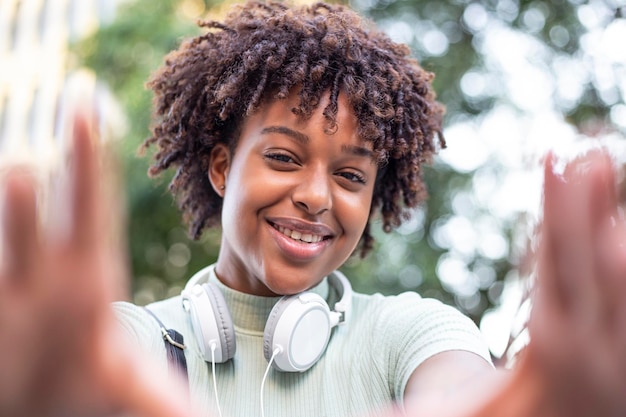 Portrait of an attractive darkskinned curlyhaired woman taking a selfie positive vibes enjoying the spring sun outdoors