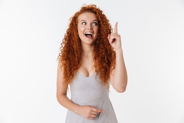 Photo portrait of an attractive excited young woman with long curly red hair standing isolated, presenting copy space