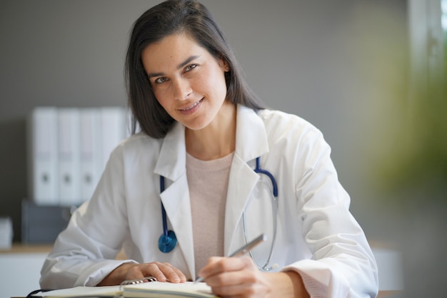 Portrait of attractive female doctor in lab coat                                                     