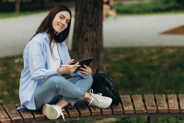 Portrait of an attractive female student wearing a blue shirt girl uses a tablet to study