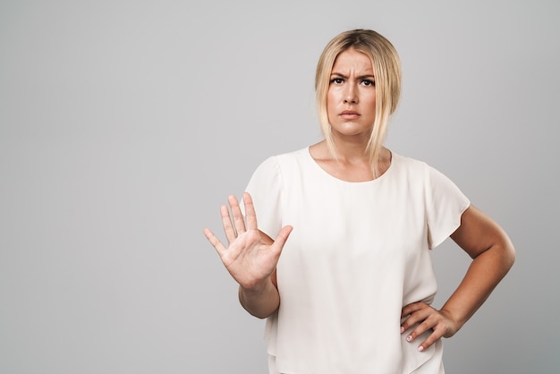 Portrait of an attractive frowning confused woman standing isolated over gray wall