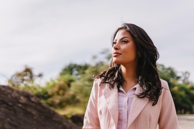 Portrait of an attractive Latin woman walking in the park at fall on a sunny day and smiling